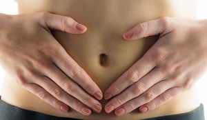 Slim woman touching her belly on white background